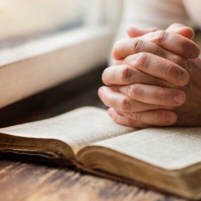 woman praying by the window with a bible