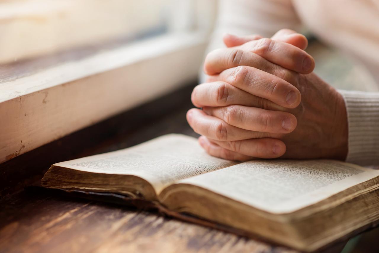 woman praying by the window with a bible